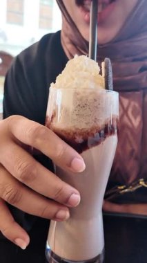 Bir insan krem şantili kremalı çikolatalı içecekten zevk alır..