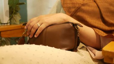 Rahatlamış bir an, bir el çantanın üzerinde dinleniyor, rahatlık sergiliyor.