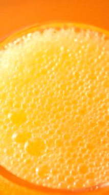 Güneşli bir ortamda servis edilen köpüklü parlak turuncu içecek..