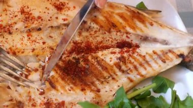 Baharat ve taze yeşilliklerle hazırlanmış ızgara balığı izlemenin tadını çıkarın..