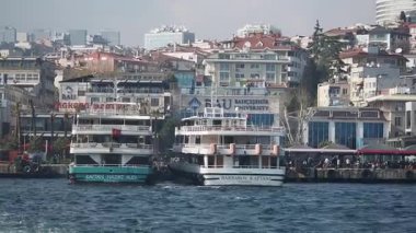 İki tekne kıyıya demirlemiş, arkasında da şehir binaları var..