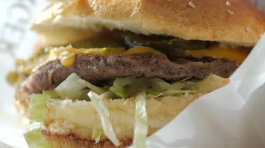 Marul, turşu ve erimiş peynirle dolu lezzetli bir hamburger..