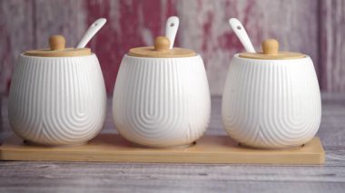 Tepside ahşap kapaklı üç zarif beyaz seramik kap..