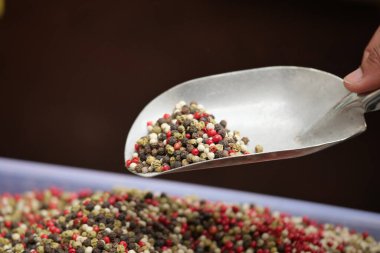 Bir el markette çeşitli biberlerle dolu bir kepçeyi tutar..