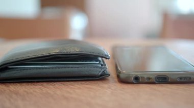 Kırsal bir ahşap masaya yerleştirilmiş bir cüzdan ve akıllı telefon..