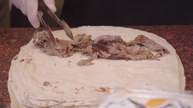 Yerel satıcı ustalıkla tavuk dürümü hazırlar. .