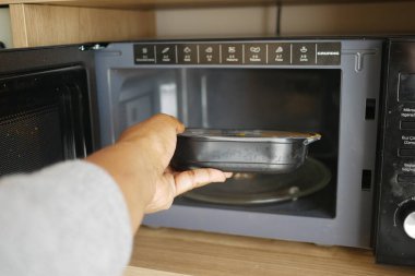 İnsan mikrodalgaya ısıtmak için bir kap koyar..