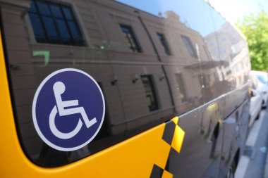 Sarı bir araç, kamuya açık tekerlekli sandalye erişim sembolü sergiler.