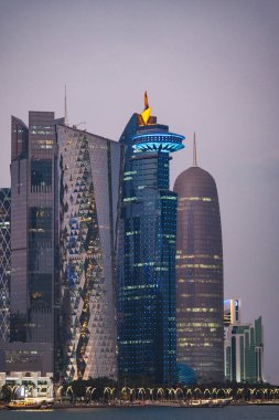 Şehrin üzerine akşam çökerken uzun binalar ışıklarla parıldıyor..