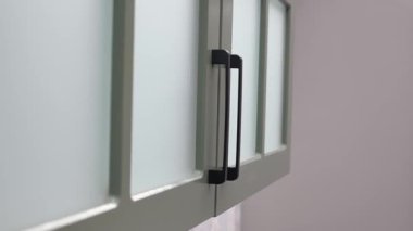 Şık dolap, aydınlık bir mutfak ortamında modern kulplara sahip..