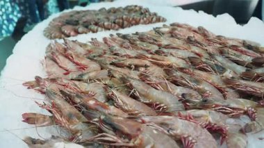 Taze karides, hareketli bir deniz ürünleri pazarında buzdan bir yatakta sergilenir..