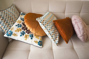 Rahat bir kanepeye dizilmiş sıcak renklerde desenli yastıklar..