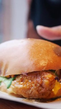 Taze malzemelerle kaplı kızarmış tavuklu sandviçin tadını çıkarıyorum..