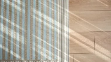 Güneş ışığı, desenli halısı ve ahşap zemini olan bir odayı aydınlatır..