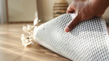 Bir el, parlak ve şık bir yaşam alanında desenli bir halıyı sarar..