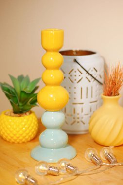 İçerideki dekoratif bitkiler ve ışıklar arasında canlı bir şamdan duruyor..