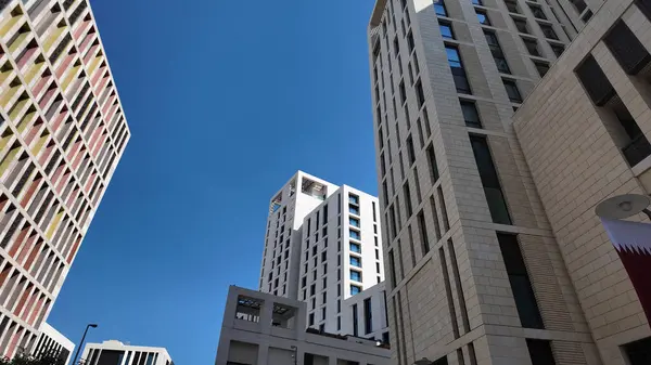 Kalabalık bir kentsel alanda mavi gökyüzüne karşı yüksek binalar yükselir..