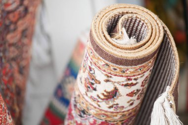 Renkli dekoratif halı, kalabalık bir pazar ortamında sergileniyor..