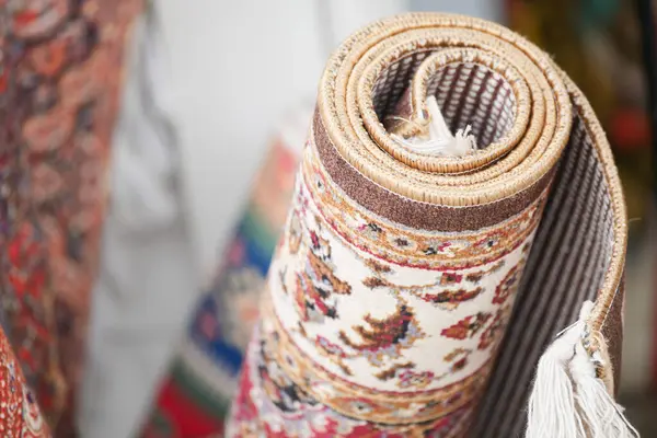 Renkli dekoratif halı, kalabalık bir pazar ortamında sergileniyor..