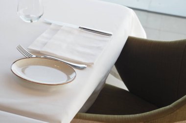 Sofra yemek için gümüş çatal bıçak ve basit bir tabakla hazırlandı..