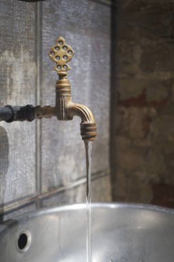 Eski bir pirinç musluk metal bir havuza temiz su döker..