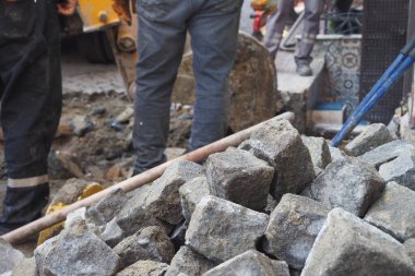 İşçiler şehirdeki bir şantiyeye taş koyuyorlar..