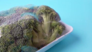 Brokoli, yemek için hazırlanan mavi bir arkaplanda sergilenir.