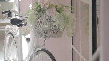 Hoş bir iç mekanda çiçeklerle süslenmiş büyüleyici beyaz bir bisiklet..