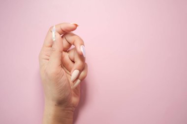 Bir el, pembe üzerinde pastel renkler olan güzel bir manikür sergiler..