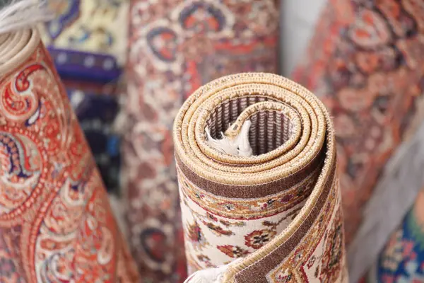 Renkli geleneksel halılar canlı bir pazar ortamında zarifçe sarılmış..