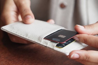 Bir insan şık bir cüzdandan kapalı bir yerden kart alır..