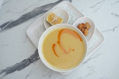 Portakal çiselemesi, limon ve kızarmış ekmekle süslenmiş bir kase kremalı çorba..