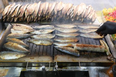 Balık filetosu ızgarada cızırdıyor. Canlı bir pazarda duman yükseliyor..