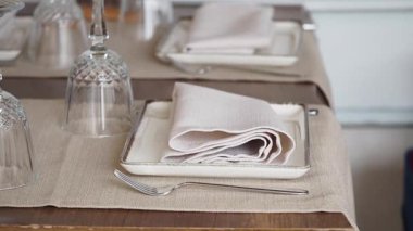 Zarif yemek düzeninde düzgünce katlanmış peçeteler ve cam eşyalar var..