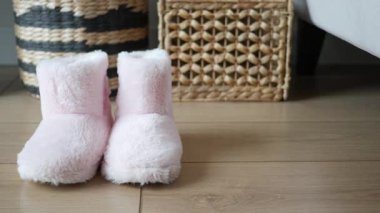 Yumuşak pembe terlikler modern bir yaşam alanında örülmüş sepetlerin yanında otururlar..