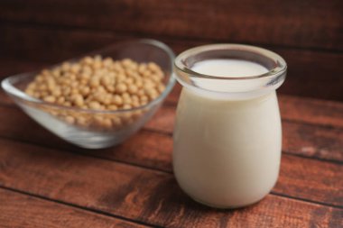 Kavanozda taze soya sütü, ahşap bir yüzeyde bir kase soya fasulyesinin yanında..