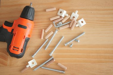 Tahtadaki çeşitli vida ve teçhizatların yanında bir matkap var..