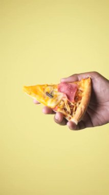 Bir insan canlı bir dilim pizzayı jambonlu ve peynirli tutuyor..