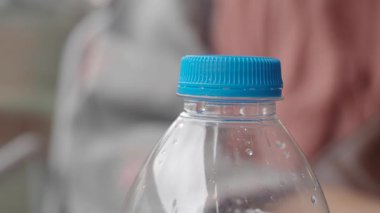 Mavi başlık ve damlacıklar sergilenen su şişesinin yakın görüntüsü.