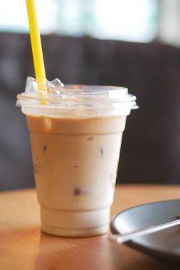 Kremalı buzlu kahve bir tabağın yanındaki ahşap masada oturur..