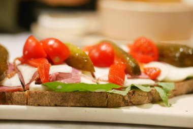 Tahta bir yüzeyde sebze ve etle dolu taze bir sandviç..