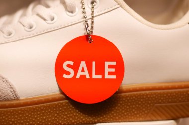 Parlak kırmızı etiket bir perakende mağazasındaki şık spor ayakkabılardan sarkıyor.