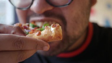 Bir adam sıcak bir yerde taze malzemelerle lezzetli bir pizzanın tadını çıkarır..