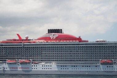 Modern bir yolcu gemisi yolcu almaya hazır, hareketli bir limanda dinleniyor..