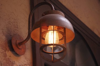 Eski bir fenerden gelen sıcak ışık dokulu bir duvarı aydınlatır..