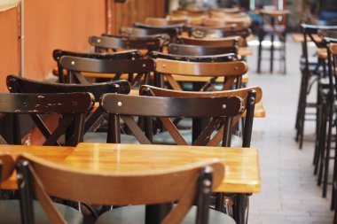 Tahta masalar ve sandalyeler açık bir kafe ortamı yaratıyor..