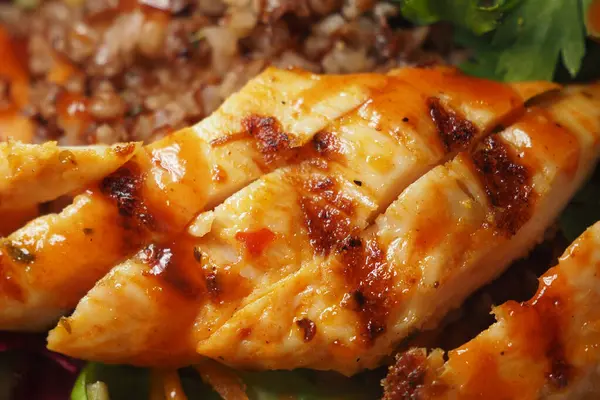 Baharatlı sosla kaplanmış sulu ızgara tavuk yeşillik yatağında duruyor..