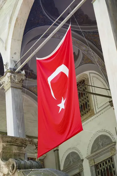Süslü bir mimaride parlak kırmızı Türk bayrağı sallanıyor.