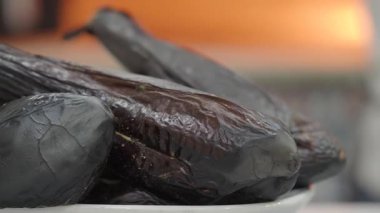 Şef patlıcan tabağını taze malzemelerle parlak bir mutfakta pişiriyor..