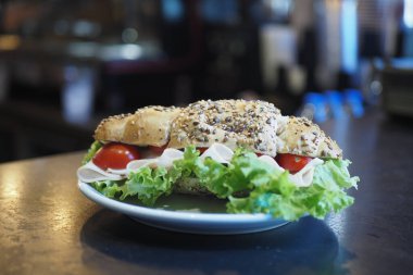 Canlı bir sandviç taze malzemeler ve ekmekle dolu bir tabakta oturur..